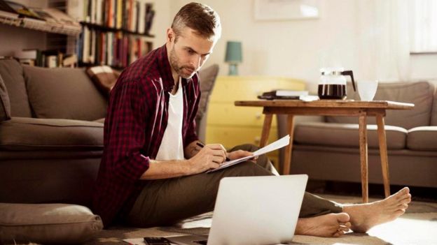 Un hombre con una laptop en la sala de su casa