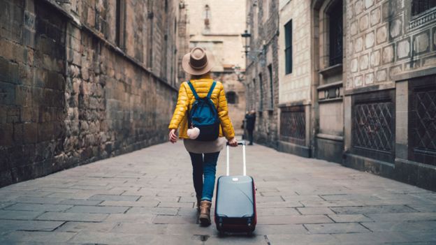Mujer caminando con una maleta por una ciudad